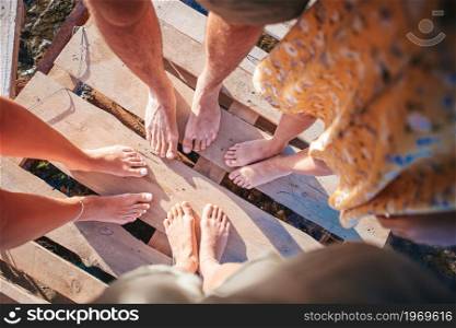 Closeup of the feet of family of parents and kids on the pier. Closeup of the feet of family on the white sandy beach