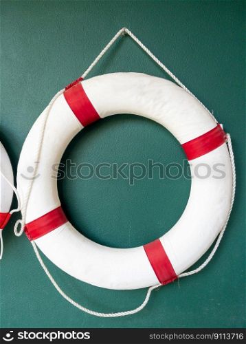 Closeup of the white lifebuoy is hanging on the green wall for decoration in the lobby of a hotel by the sea, front view with the copy space.