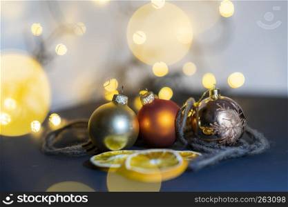 Closeup of three colorful christmas ball surrounded by bokeh balls and blurred out background, dryed oranges, giving the christmas feeling