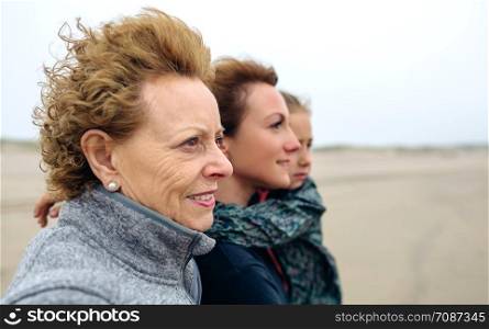Closeup of three generations female looking at sea on the beach in autumn. Three generations female looking at sea