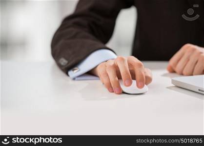 Closeup of torso of confident business man wearing elegant suit working with his laptop at office