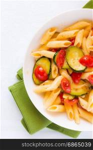 Closeup of traditional italian penne pasta with zucchini and cherry tomatoes seen from above. Italian penne pasta with zucchini and cherry tomatoes