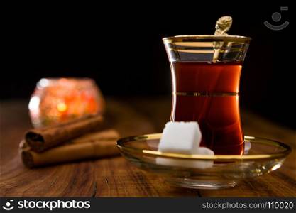 Closeup of Turkish tea in traditional glass over a wooden background in backlight. Turkish tea in traditional glass