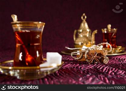 Closeup of Turkish tea in traditional glass with star anise and cinnamon sticks. Turkish tea in traditional glass