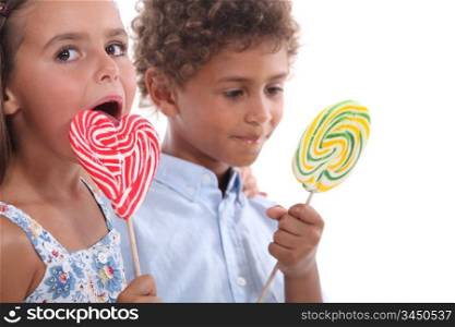 Closeup of two children eating lollipops