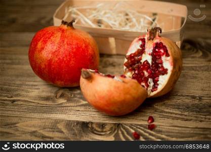 Closeup of two halves of pomegranate on old wooden board