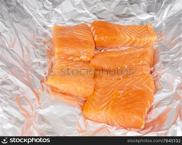 Closeup of unseasoned salmon pieces in aluminum foil