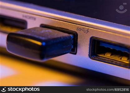 Closeup of USB flash drive inserted into port on the side of a laptop.