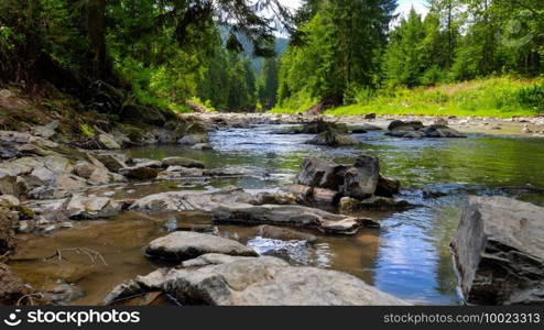 Closeup of wet rocks and calm flowing water on the beautiful mountain river flowing through pine forest.. Closeup of wet rocks and calm flowing water on the beautiful mountain river flowing through pine forest