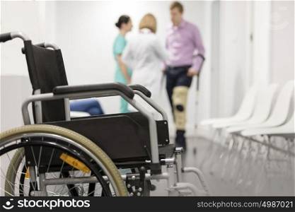 Closeup of wheelchair against patient and doctors at hospital