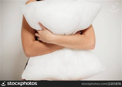 Closeup of white pillow in female arms on gray. Relax in the bedroom at the morning or evening. Lazy sunday in the bed.