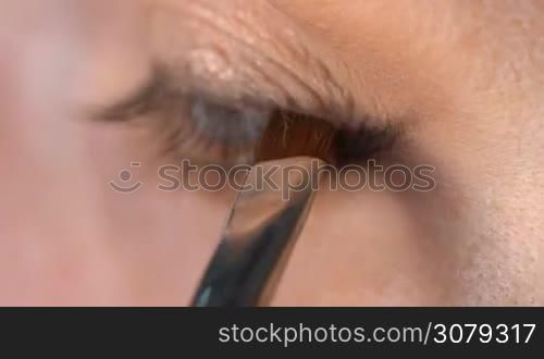 Closeup of woman&acute;s eye applying eyeliner. Woman smudging eyepencil with small brush