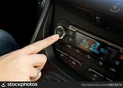 Closeup of woman adjusting temperature on car climate control system