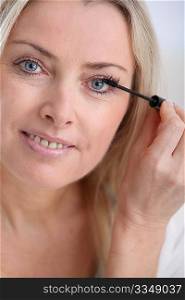 Closeup of woman applying mascara on eyelashes