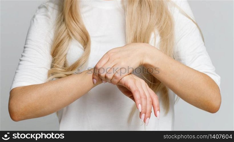Closeup of woman arms holding her painful wrist caused by prolonged work on the computer, laptop. Carpal tunnel syndrome, arthritis, neurological disease concept. Numbness of the hand