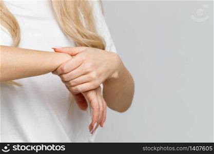 Closeup of woman arms holding her painful wrist caused by prolonged work on the computer, laptop. Carpal tunnel syndrome, arthritis, neurological disease concept. Numbness of the hand. Copy space.