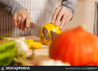 Closeup of woman cutting a yellow pepper