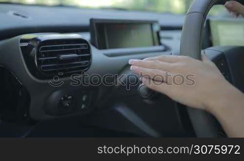 Closeup of woman driving car and using turn signal switch