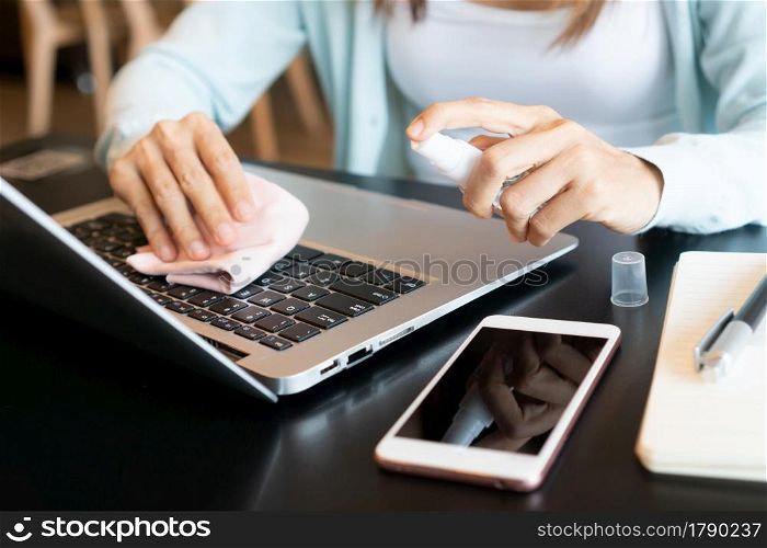 Closeup of woman hands cleaning her laptop. Disinfect surfaces, high touch and daily use item to prevent the coronavirus disease pandemic, hygiene concept.