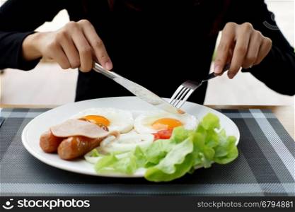 closeup of woman hands holding knife and fork during eating breakfast