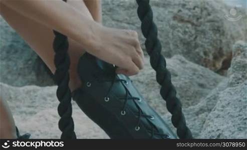 Closeup of woman hands tying and adjusting shoelaces outdoor - video in slow motion