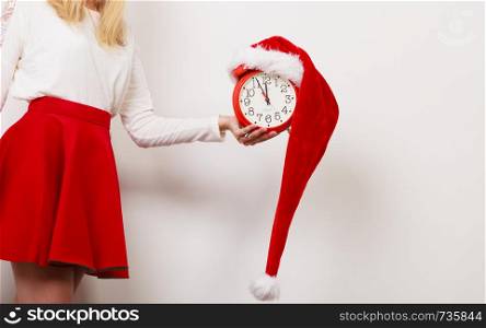 Closeup of woman holding alarm clock with santa claus hat. Christmas time season concept.. Woman with alarm clock. Christmas time.