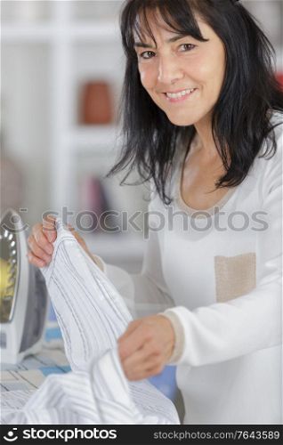 closeup of woman ironing clothes on ironing board