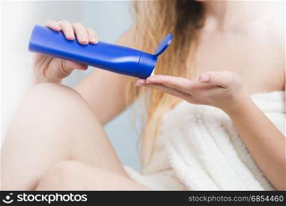 Closeup of woman pouring body lotion on hand after having bath