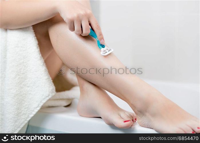 Closeup of woman shaving legs after having bath
