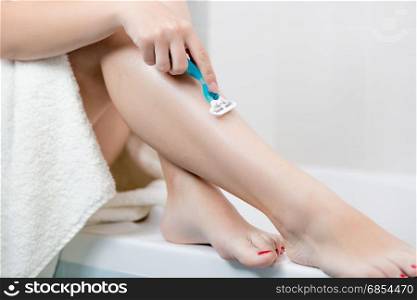 Closeup of woman shaving legs after having bath