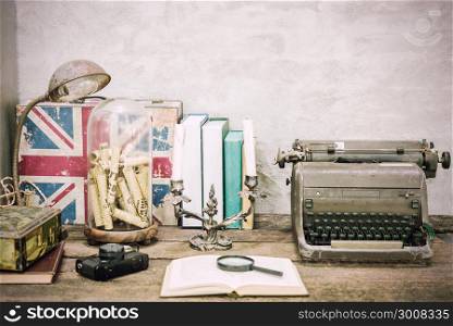 Closeup of workplace with open book stationery items and retro lamp on wooden table with white concrete background.Vintage filtered. Education concept. Reading and researching concept.