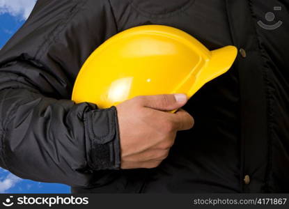 Closeup of Yellow helmet at builder hands on building background