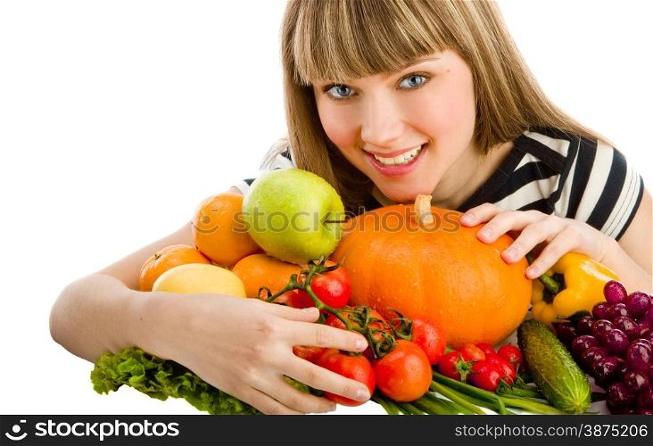 Closeup of young beautiful smiling woman embracing a big group of fruit and vegetables . Looking at camera.