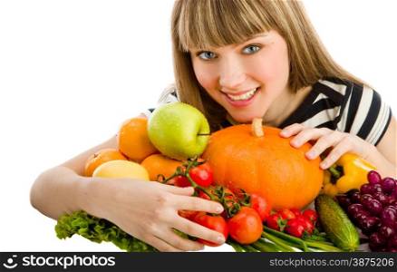 Closeup of young beautiful smiling woman embracing a big group of fruit and vegetables . Looking at camera.