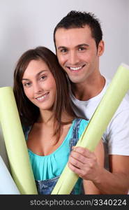 Closeup of young couple holding wallpaper rolls
