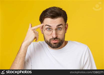 Closeup of young handsome man looking and showing funny face at camera, wearing glass. Isolated view on yellow background. Closeup of young handsome man looking and showing funny face at camera, wearing glass. Isolated view on yellow background.