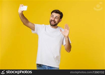Closeup of young handsome man looking at smartphone and taking selfie. isolate over yellow background. Closeup of young handsome man looking at smartphone and taking selfie. isolate over yellow background.
