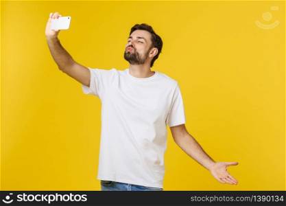 Closeup of young handsome man looking at smartphone and taking selfie. isolate over yellow background. Closeup of young handsome man looking at smartphone and taking selfie. isolate over yellow background.