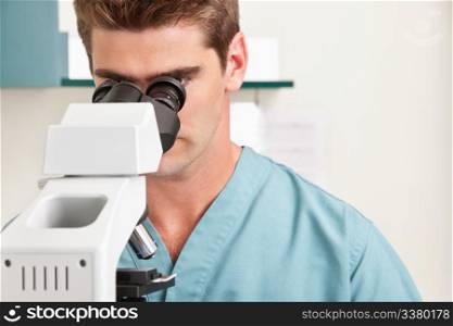 Closeup of young male doctor viewing through microscope
