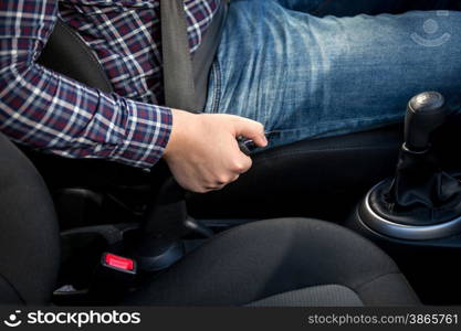 Closeup of young man pulling handbrake lever in car