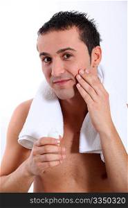 Closeup of young man putting moisturizer on his face