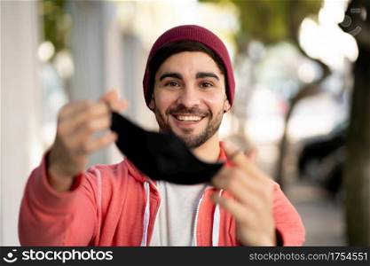 Closeup of young man putting on face mask while standing outdoors at the street. Urban concept. New normal lifestyle concept.
