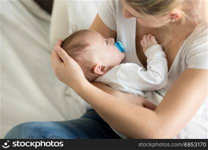Closeup of young mother with her sleeping baby at bedroom