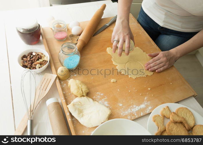 Closeup of young woman cutting dough with glass