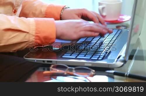 Closeup of young woman using and typing on laptop computer
