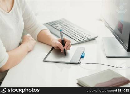 Closeup of young woman using graphic tablet at office