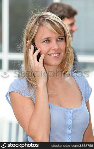 Closeup of young woman with mobile phone at college campus