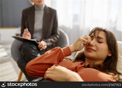 Closeup of young woman with problem suffering from depression crying on psychologist therapy session. Closeup of young woman with problems crying