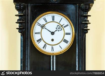 Closeup old big wooden pendulum clock hanging on wall