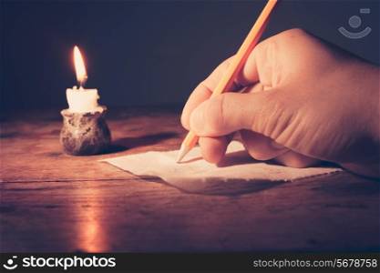 Closeup on a hand writing by candlelight